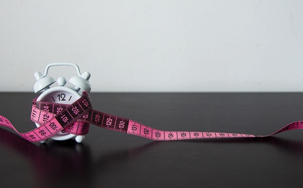 A clock with a measuring tape wrapped around it to represent ‘How long does it take for Mounjaro to work?’