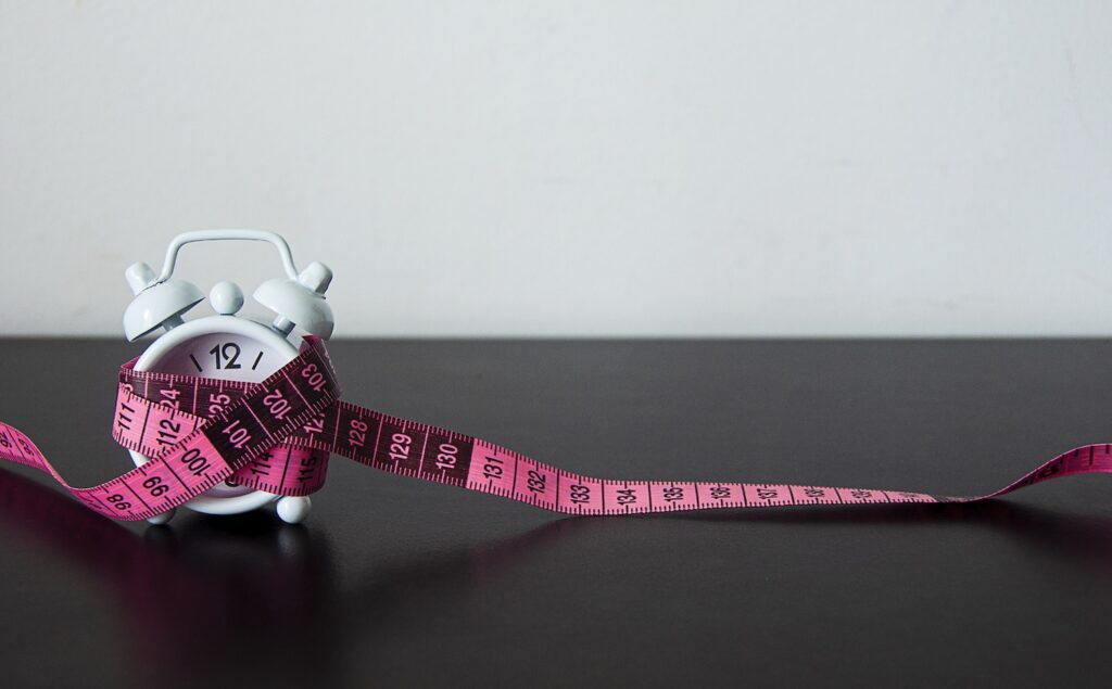 A clock with a tape measure wrapped around it to represent ‘How long can you stay on Wegovy?’