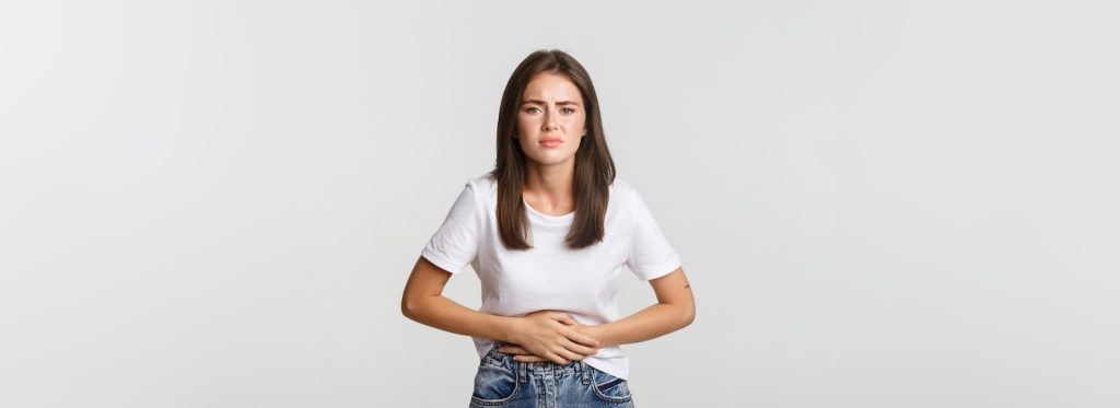 A woman holding her tummy to represent ‘What causes a UTI in women?’