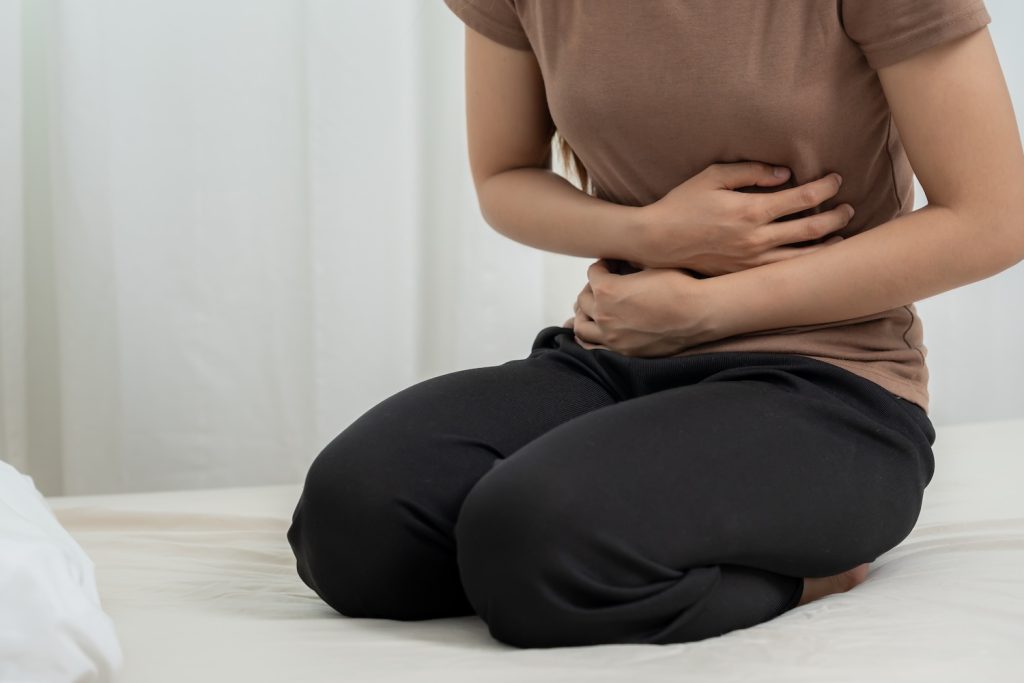 A woman with cramps wondering how to reduce heavy menstrual bleeding during periods