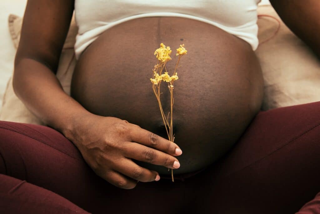A woman holding a flower in front of her pregnant belly, wondering about Mounjaro and pregnancy