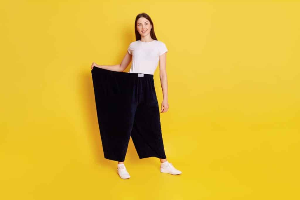 A woman standing in trousers too big to show weight loss after she compared nevolat vs wegovy