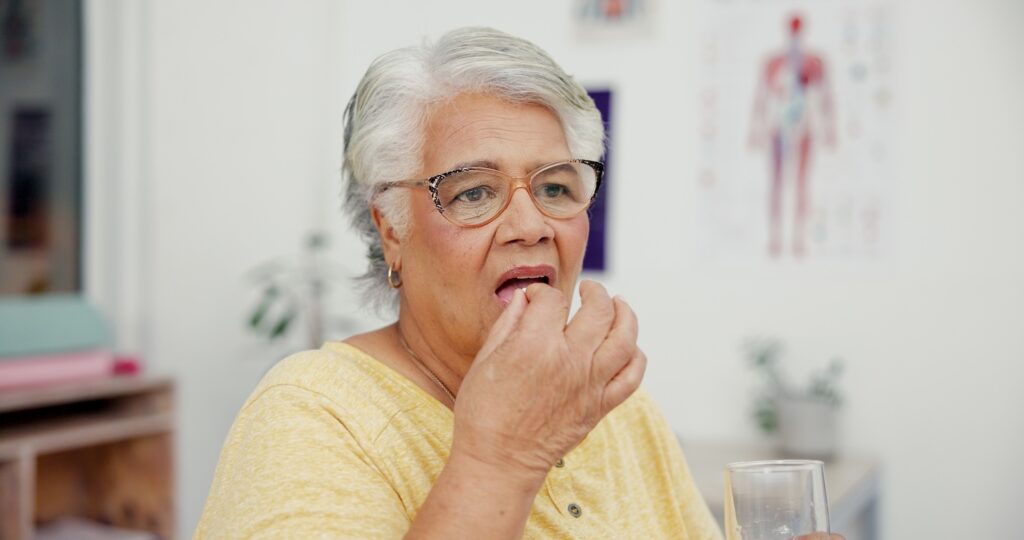 An older woman taking a weight loss pill considering the differences between foundayo pill vs wegovy pill