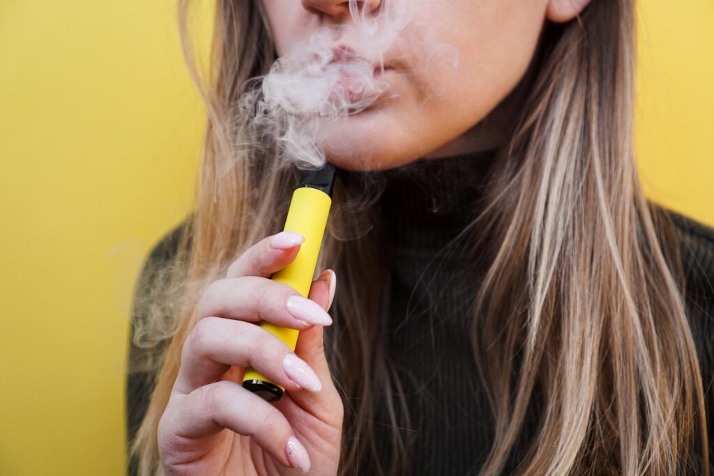 A woman vaping a yellow e-cigarette considering how do I stop vaping